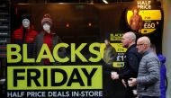 People walk past a sign advertising Black Friday offers in the window of a Blacks outdoor clothing store in Manchester, Britain, November 22, 2019. Reuters/Phil Noble