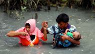 Rohingya refugees carry their child as they walk through water after crossing border by boat through the Naf River in Teknaf, Bangladesh, September 7, 2017. Reuters / Mohammad Ponir Hossain