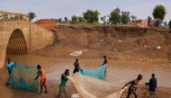 Residents of Yusuf Batir refugee camp fish together with the local host community at a stream formed as a result of intense flooding in Maban, South Sudan on November 26, 2019. AFP / Alex McBride
 