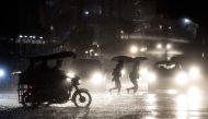 File photo: People cross a road during heavy rain caused by Typhoon Maliksi in Manila on June 10, 2018. AFP / Noel Celis