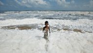 A boy plays with foam formed from pollution at the Marina beach in Chennai, India, November 29, 2019. REUTERS/P. Ravikumar

