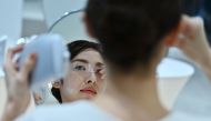 An employee for Japanese cosmetics company Kao uses a palm-sized diffuser on her face, during a product demonstration in Tokyo on December 4, 2019. AFP / CHARLY TRIBALLEAU