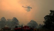 A firefighter talks on a radio as an out-of-control bushfire burns at Avery's Lane, Australia, December 3, 2019. Picture taken December 3, 2019. AAP Image/Darren Pateman/via REUTERS 