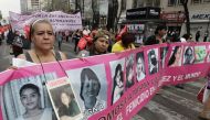 Norma Andrade Ledezma, a Mexican woman with a picture of her 17-year-old daughter who was murdered in Ciudad Juarez, walks with a banner during a protest demanding justice for the victims of violence at a closed street near Mexico's Interior Ministry buil