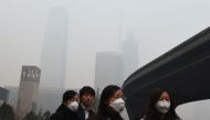 People wear masks on a polluted day in Beijing on December 9, 2015. AFP