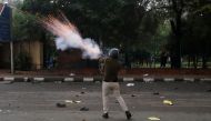 A police officer fires a teargas shell towards a protest against the Citizenship Amendment Bill outside the Jamia Millia Islamia University in New Delhi, India, December 13, 2019. REUTERS/Adnan Abidi