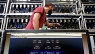 An employee works on Bitcoin mining computer as a PC screen shows the fluctuations in Bitcoin exchange rates at Bitminer Factory in Florence, Italy, April 6, 2018. Reuters/Alessandro Bianchi