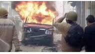 Police personnel look at a burning vehicle during clashes over citizenship law in Bulandshahar, Uttar Pradesh, India December 20, 2019 in this still image taken from a video. 