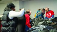 People in need of coats pick from a table of jackets on December 24, 2019 in New York City. New York Cares has collected 50,000 of the 100,000 coats it aims to collect and distribute to its hundreds of school and nonprofit partners in the 31st annual coat