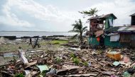 Residents walk past a house damaged during Typhoon Phanfone in Tacloban, Leyte province in the central Philippines on December 25, 2019. / AFP / Bobbie ALOTA 