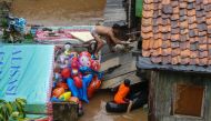 A man tries to capture his goose from the roof of their home as they evacuate after rain all night caused local flooding in certain areas in Jakarta on January 1, 2020. / AFP / BAY ISMOYO
