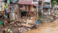 Indonesians clean their homes and cutlery along the river in Jakarta on January 3, 2020, after flooding triggered by heavy rain which started on New Year's Eve hit the area. / AFP / BAY ISMOYO 