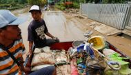 Men collecting damaged items ride on the back of a car through the mud, at a residential area affected by floods in Bekasi, West Java province, Indonesia, January 3, 2020. REUTERS/Willy Kurniawan