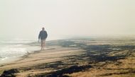Local resident Dave Iredale walks past ash from bushfires washed up on a beach in Merimbula, in Australia's New South Wales state on January 5, 2020. Australians on January 5 counted the cost from a day of catastrophic bushfires that caused 