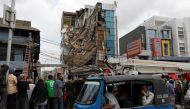 People in a three-wheeler pass a partially-collapsed building in Jakarta, Indonesia, January 6, 2020. REUTERS/Willy Kurniawan