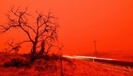 TOPSHOT - A long exposure picture shows a car commuting on a road as the sky turns red from smoke of the Snowy Valley bushfire on the outskirts of Cooma on January 4, 2020. Up to 3,000 military reservists were called up to tackle Australia's relentless bu