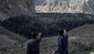 This picture taken on June 28, 2019 shows men pointing at the black Shisper glacier in the Karakoram mountain range of Pakistan's Gilgit-Baltistan region. AFP / Aamir Qureshi