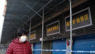 A woman walks in front of the closed Huanan wholesale seafood market, where health authorities say a man who died from a respiratory illness had purchased goods from, in the city of Wuhan, Hubei province, on January 12, 2020. AFP / Noel Celis
 