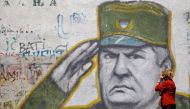 A woman walks past graffiti of Bosnian Serb wartime general Ratko Mladic in a suburb of Belgrade, Serbia, May 27, 2011. Reuters / Stoyan Nenov