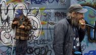 Homeless men eat hot dogs handed out from a soup kitchen handed out in a vacant lot in downtown Vancouver, November 22, 2001. Reuters/Andy Clark