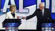 File photo: Hillary Clinton reacts as rival Bernie Sanders tries to hand her a piece of paper during a Democratic debate IN 2016. 