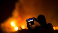 A woman uses her mobile phone to film as a forest fire burns out of control in Las Manchas on the southwestern part of La Palma island, Spain, August 5, 2016. Reuters / Borja Suarez