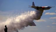 A television reporter stands in front of a Large Air Tanker (LAT) C-130 Hercules as it drops a load of around 15,000 litres during a display by the Rural Fire Service ahead of the bushfire season at RAAF Base Richmond Sydney, Australia, September 1, 2017.