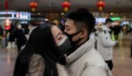 A couple, wearing protective masks, kisses goodbye as they travel for the Lunar New Year holidays, at Beijing West Railway Station in Beijing on January 24, 2020. AFP / Nicolas Asfouri
 