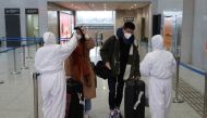 Workers in protective suits check the temperature of passengers arriving at the Xianning North Station on the eve of the Chinese Lunar New Year celebrations, in Xianning, a city bordering Wuhan to the north, in Hubei province, China January 24, 2020. REUT