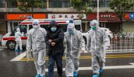 This photo taken on January 26, 2020 shows medical staff members wearing protective clothing to help stop the spread of a deadly virus which began in the city, accompanying a patient (2nd L) as they walk into a hospital in Wuhan in China's central Hubei p