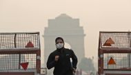 FILE PHOTO: A man wearing a mask runs past the India Gate on a smoggy morning in New Delhi, India, October 28, 2019 REUTERS/Adnan Abidi/File Photo 