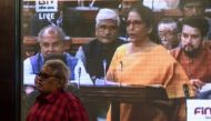 A man (L) walks past a screen displaying a television channel live broadcast of India's Finance Minister Nirmala Sitharaman (3R on screen) presenting the 2020 union budget at the Bombay Stock Market (BSE) in Mumbai on February 1, 2020. (AFP / Punit PARANJ