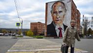 An elderly woman crosses a road in front a mural painting depicting Russian President Vladimir Putin in the town of Kashira, some 115 km southeast of Moscow on October 16, 2017. AFP / Vasily Maximov