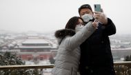 People wearing face masks take selfies at Jingshan Park, as the country is hit by an outbreak of the new coronavirus, in Beijing, China February 5, 2020. REUTERS/Carlos Garcia Rawlins