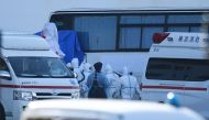 People wearing protective suits arrange a blue cover on a bus near the Diamond Princess cruise ship, with around 3,600 people quarantined onboard due to fears of the new coronavirus, at the Daikoku Pier Cruise Terminal in Yokohama port on February 11, 202