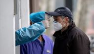 An elderly man wearing a face mask has his temperature checked before entering a community hospital in Shanghai on February 13, 2020. AFP / NOEL CELIS