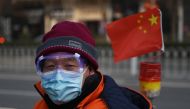 A cleaner wears a mask and goggles as he commutes on a street in Beijing on February 11, 2020.  / AFP / GREG BAKER