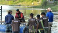 This picture taken on February 11, 2020, shows Australian crocodile wranglers Matthew Nicolas Wright (R) and Chris Wilson (L) directing the lndonesian team in setting the trap in the river in Palu, Sulawesi. AFP / Olagondronk