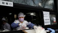 An employee deliver buns to a customer through a ramp from the restaurant counter at a store, as the country is hit by an outbreak of the novel coronavirus, in Beijing, China February 12, 2020. Reuters/Carlos Garcia Rawlins