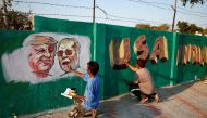 A man applies finishing touches to paintings of Donald Trump and Narendra Modi on a wall as part of a beautification along a route that they will be taking during Trump visit in Ahmedabad, India, February 17, 2020. Reuters/Amit Dave 
 