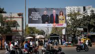 People ride their motorbikes past a hoarding with the images of India's Prime Minister Narendra Modi, U.S. President Donald Trump and first lady Melania Trump ahead of Trump's visit, in Ahmedabad, India, February 18, 2020. REUTERS/Amit Dave
 