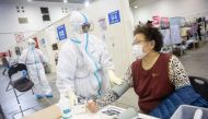 This photo taken on February 17, 2020 shows a member of the medical staff (C) taking the blood pressure of a woman who has displayed mild symptoms of the COVID-19 coronavirus at an exhibition centre converted into a hospital in Wuhan in China's central Hu
