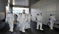 This picture taken on February 19, 2020 shows South Korean health officials wearing protective suit and spraying disinfectant near a church in the southeastern city of Daegu as about 40 new cases of the COVID-19 coronavirus confirmed after they attended s