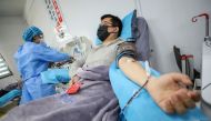 This photo taken on February 18, 2020 shows a doctor (R) who has recovered from the COVID-19 coronavirus infection donating plasma in Wuhan in China's central Hubei province. China OUT / AFP / STR