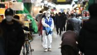A worker from the Korea Pest Control Association, wearing protective gear, sprays disinfectant to help prevent the spread of the COVID-19 novel coronavirus at a market in Seoul on February 24, 2020. / AFP / Jung Yeon-je 
