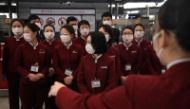 Air China staff position themselves to take a group photo after putting smiley face stickers on their masks, worn as a preventive measure against the  coronavirus on February 24, 2020.(AFP / GREG BAKER)