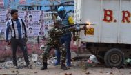 A police officer fires a tear gas shell to disperse crowds after a clash between people supporting a new citizenship law and those opposing the law, in Maujpur area of New Delhi, India, February 23, 2020. (REUTERS/Akash Jain)