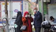 People wearing protective masks wait along the side of a street in the Iranian capital Tehran on February 24, 2020.   AFP / ATTA KENARE
