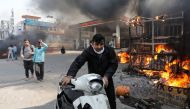 A man pushes his damaged scooter past a burning petrol pump during a clash between people supporting a new citizenship law and those opposing it, in New Delhi India, February 24, 2020. REUTERS/Danish Siddiqui