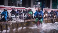A cyclist rides alongside motorcyclists along a flooded street in Jakarta, Indonesia, February 25, 2020 in this photo taken by Antara Foto. Antara Foto/Aprillio Akbar/ via REUTERS